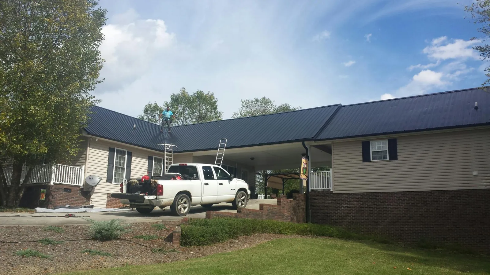 Black metal roof over a home and attached breezeway with ladders set in Newfoundland
